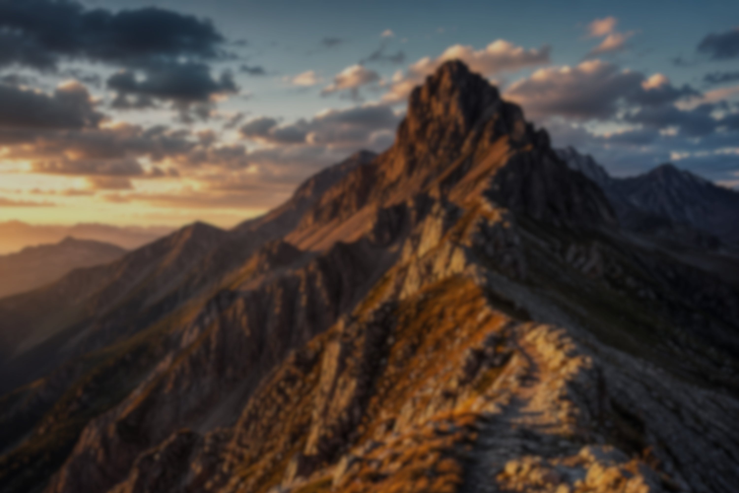 Mountain peak at sunset with warm light and clouds in the sky