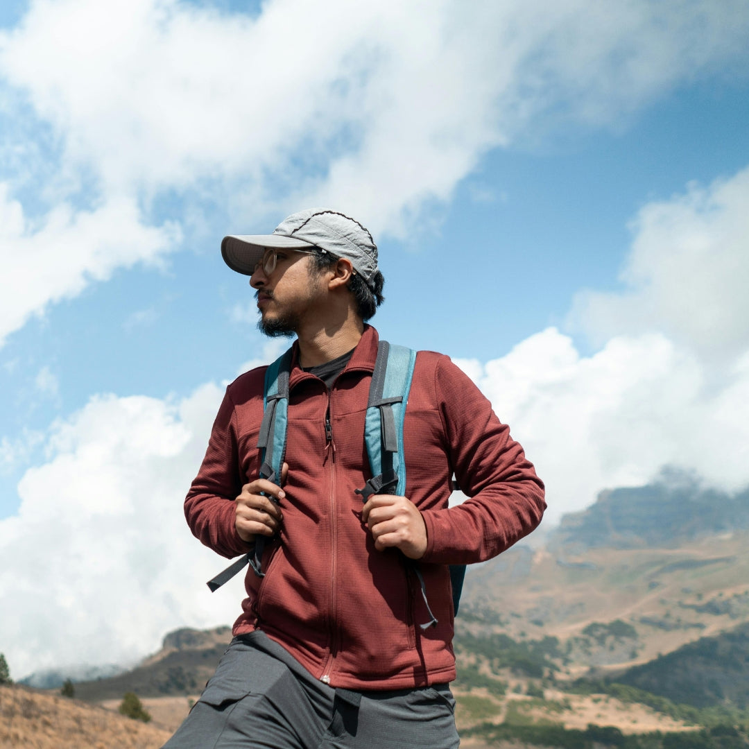 Male hiker wearing a red jacket and backpack exploring mountain trails.