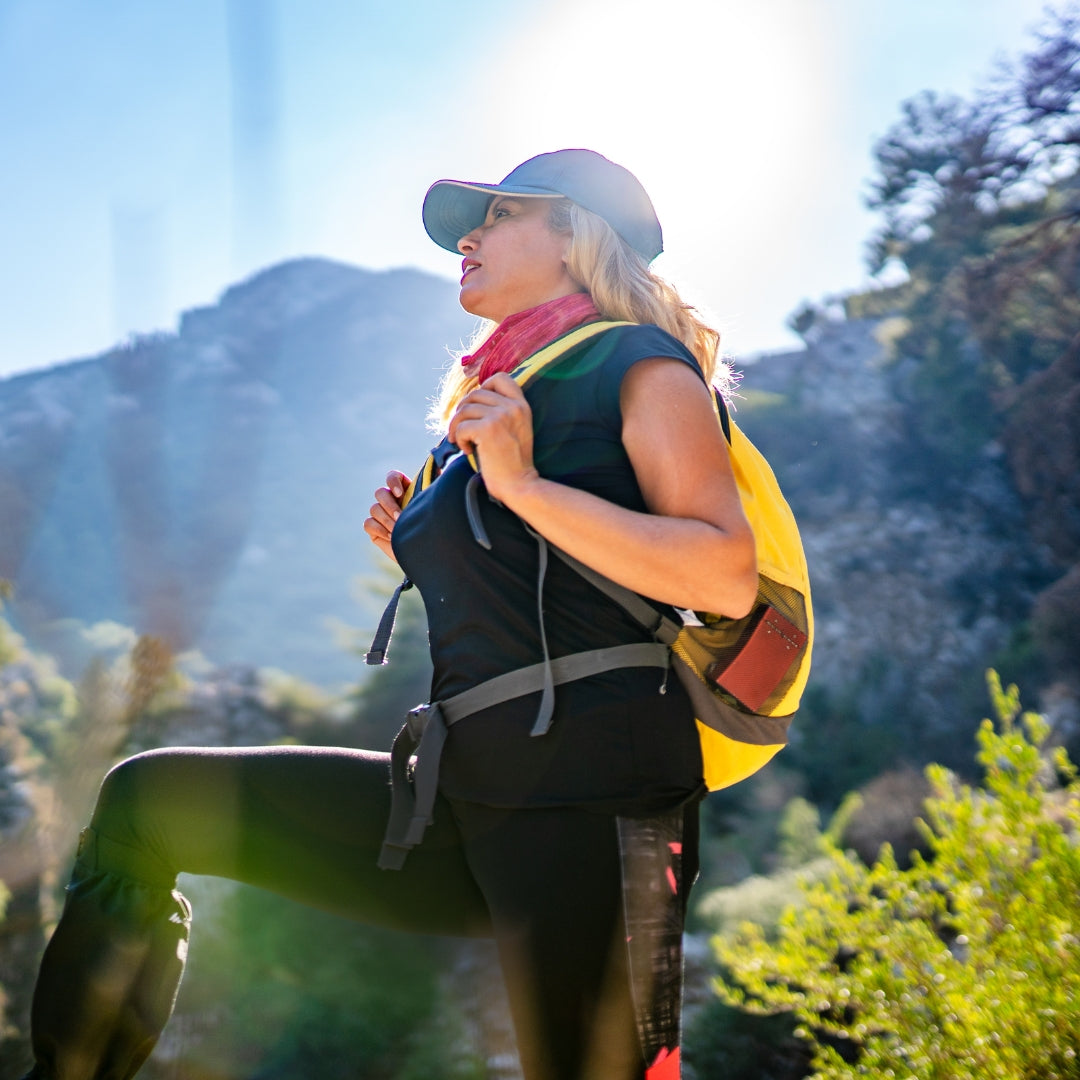 Woman hiking with a yellow backpack in a mountainous area